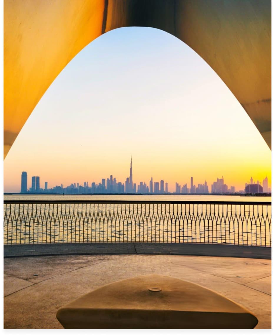 City skyline seen through a large architectural arch at dusk