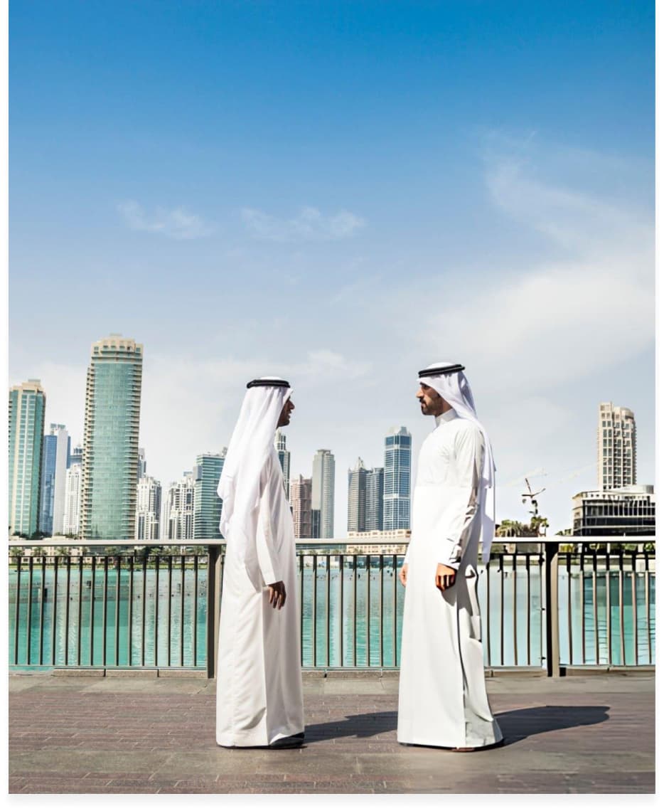 Two partners talking on a waterfront promenade with the city behind them